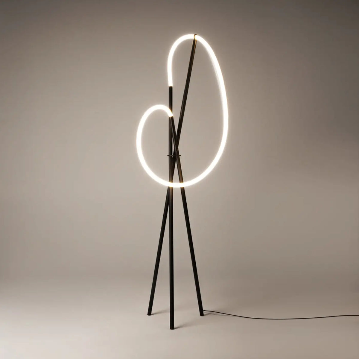 Lampadaire trépied doré éclairant un salon contemporain le soir