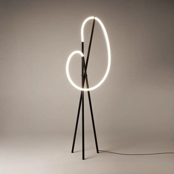 Lampadaire trépied doré éclairant un salon contemporain le soir