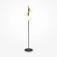 Lampadaire trois globes opalins placé près d'un canapé moderne