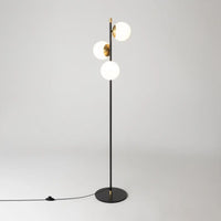 Lampadaire trois globes opalins diffusant une lumière chaude tamisée