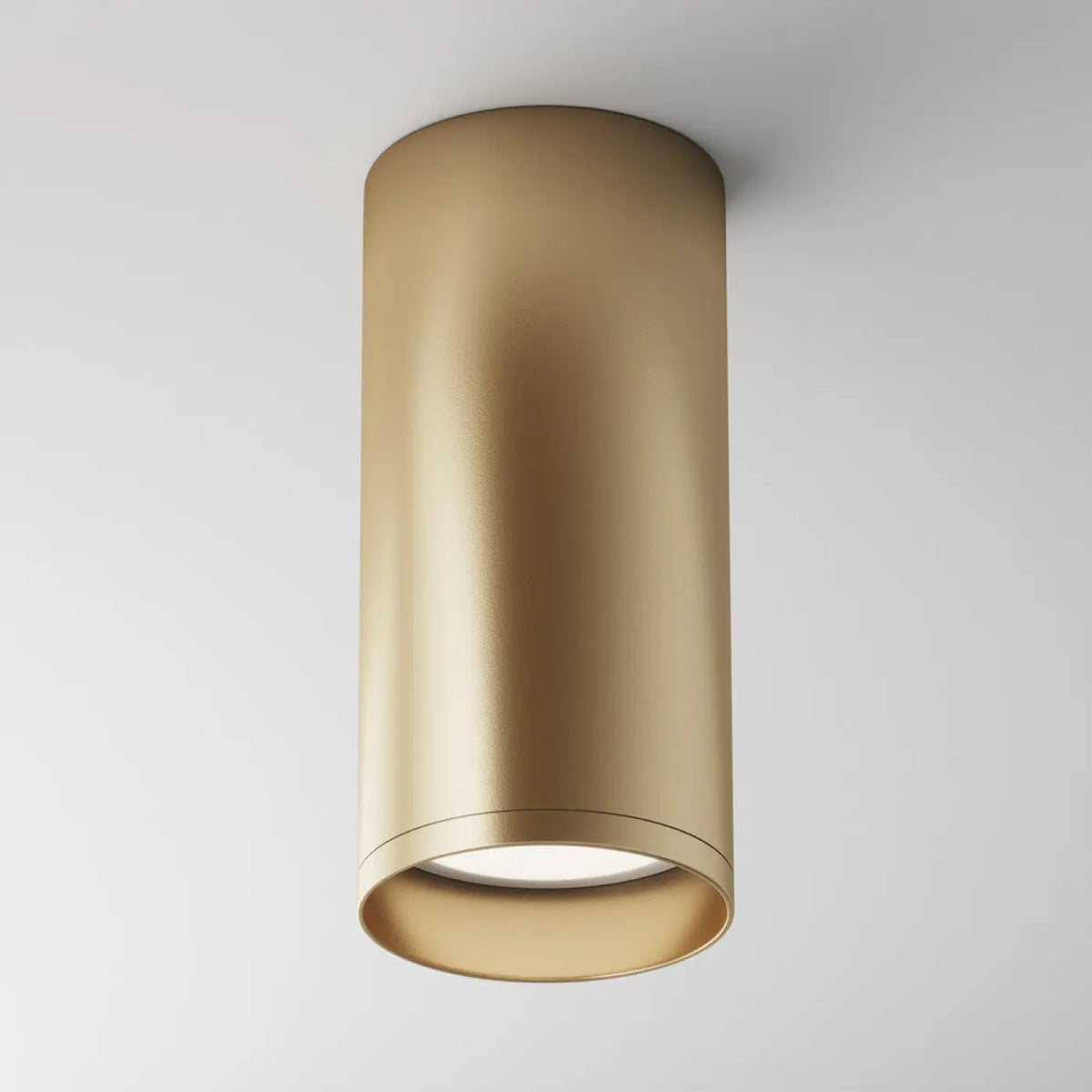 Spot cylindrique en acier doré apportant une touche chaleureuse à l'intérieur