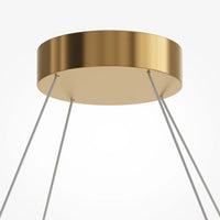 Suspension anneau doré installée dans un salon au plafond haut