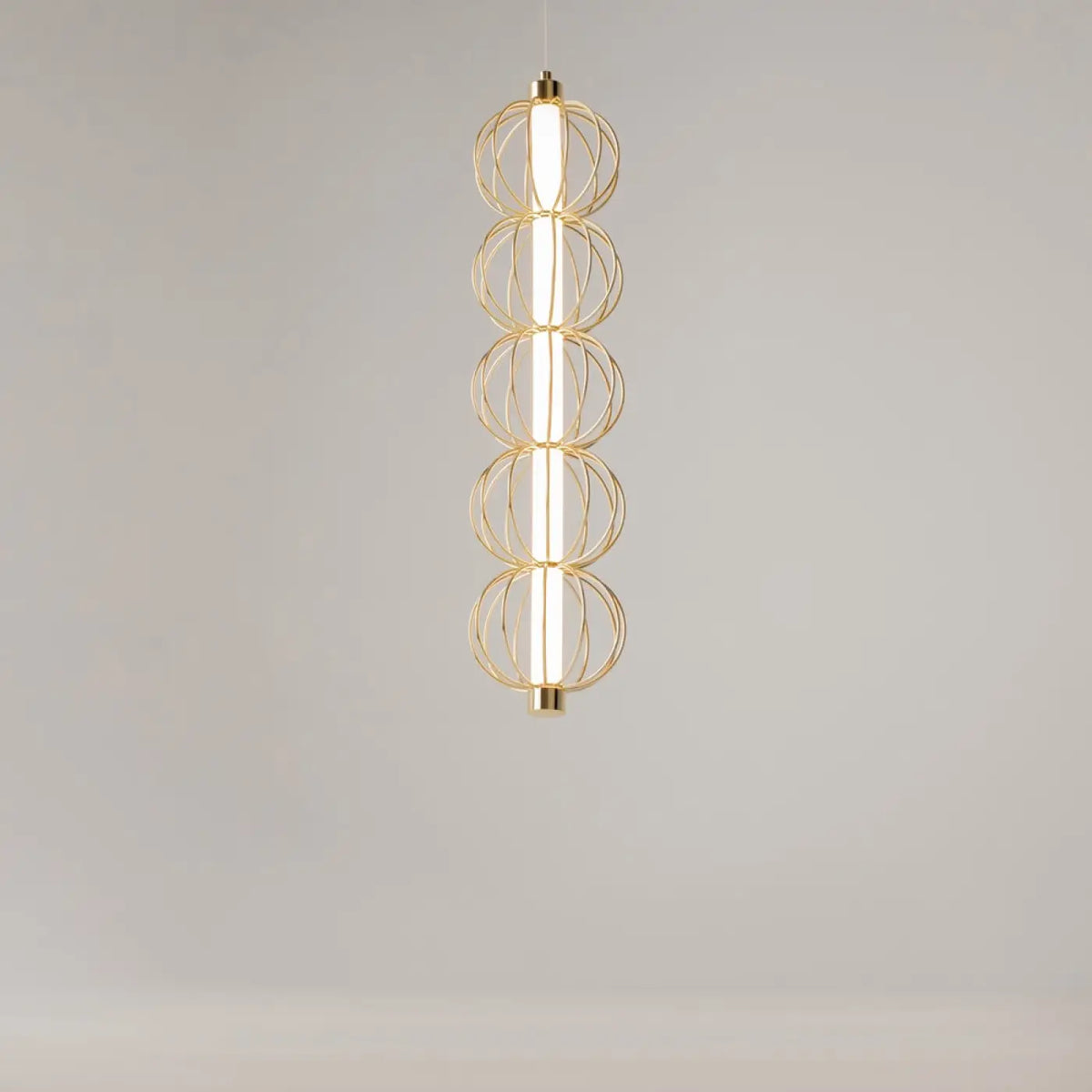 Détail de la suspension cage dorée diffusant une lumière blanche chaude