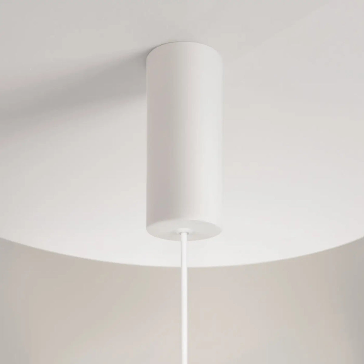 Suspension LED blanche suspendue dans un salon aux tons neutres